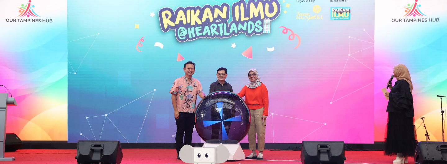 Three people behind a large sphere with an elephant-shaped base, on stage in front of an event banner.